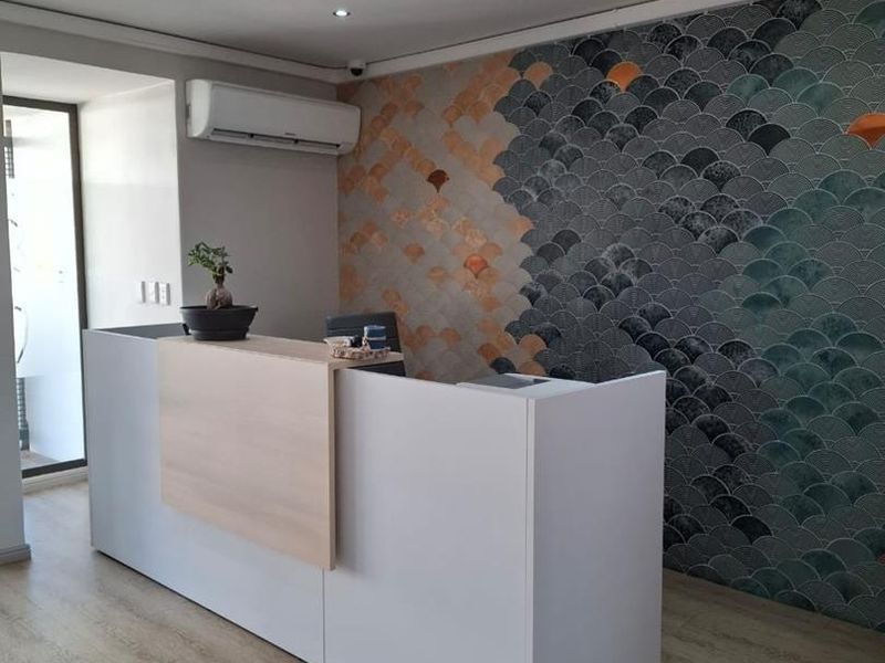 Modern office reception area featuring a custom built-in desk, decorative feature wall tiling, and integrated air conditioning.