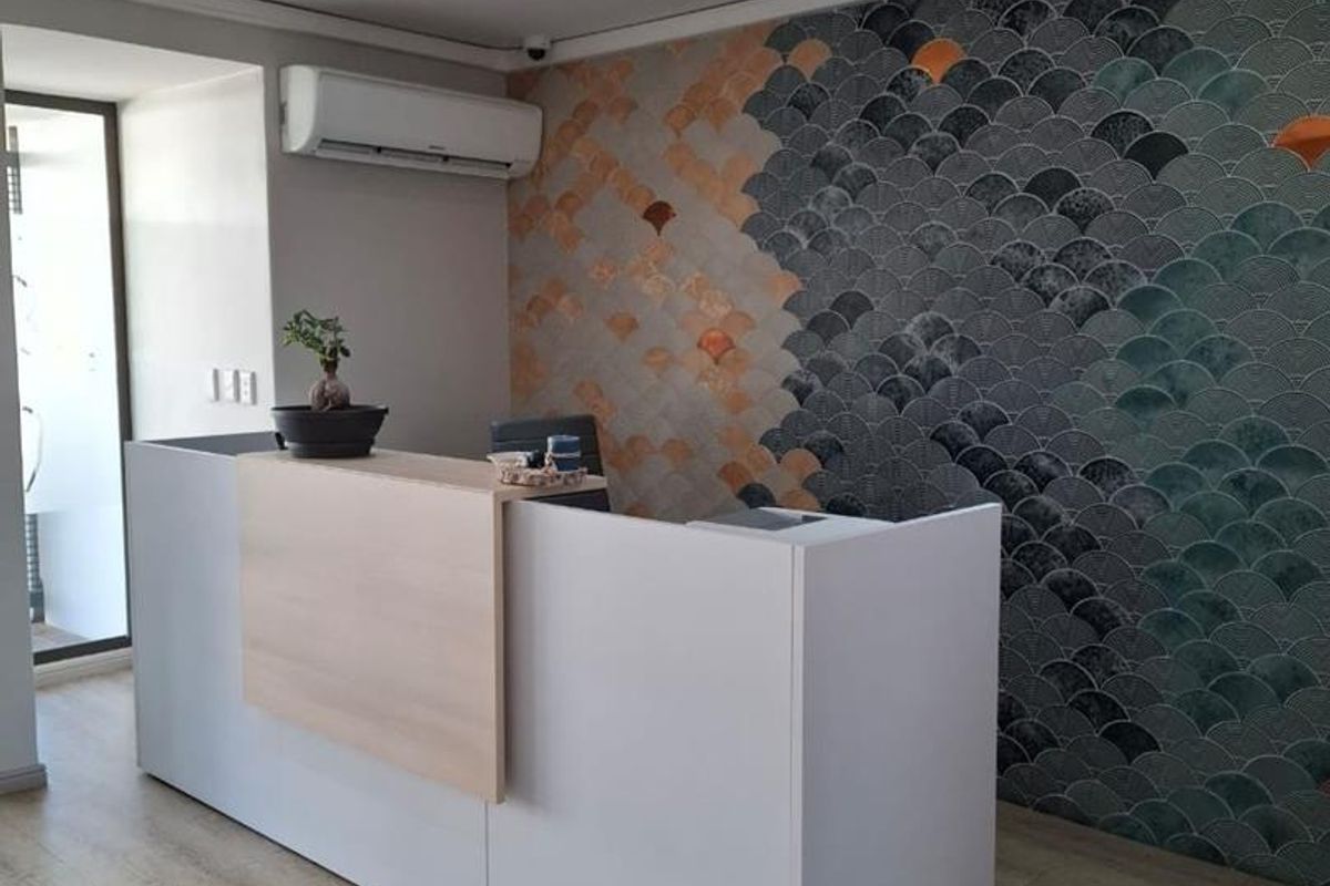 Modern office reception area featuring a custom built-in desk, decorative feature wall tiling, and integrated air conditioning.