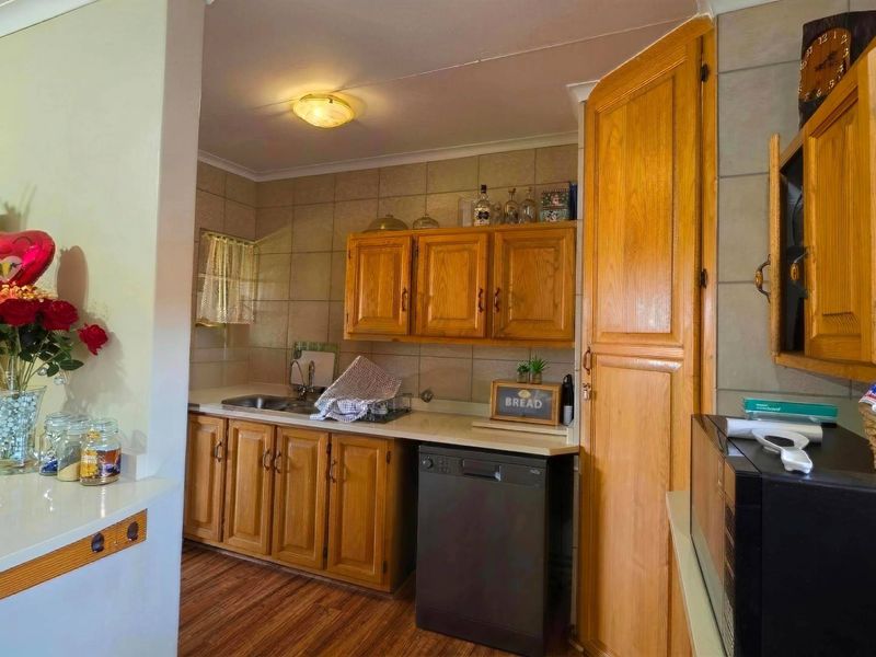 A functional kitchen featuring traditional wooden cabinetry, tiled backsplash, and laminate countertops, offering a classic layout with integrated dishwasher and ample storage space.