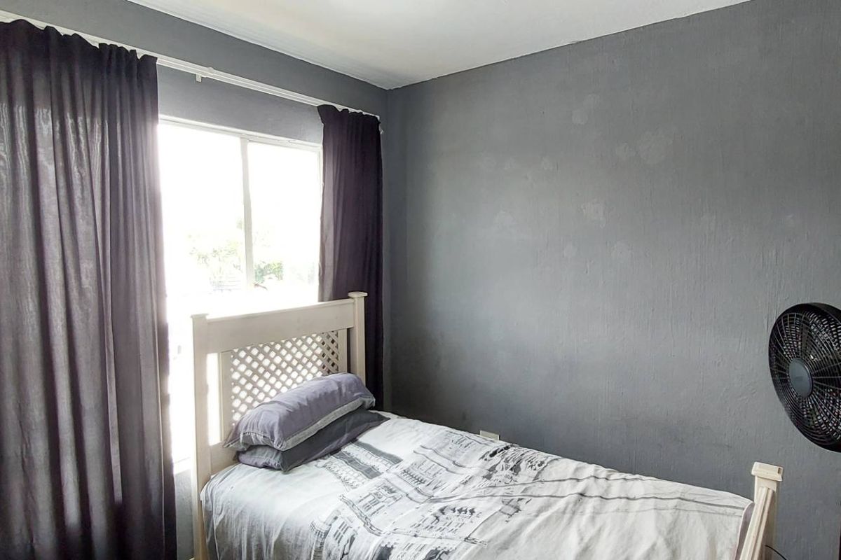 A bedroom featuring grey painted walls and a window with curtain tracks.