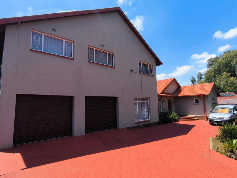 Front view of a double-story house featuring a double garage, paved driveway, and tiled roof, set in a well-maintained residential area.