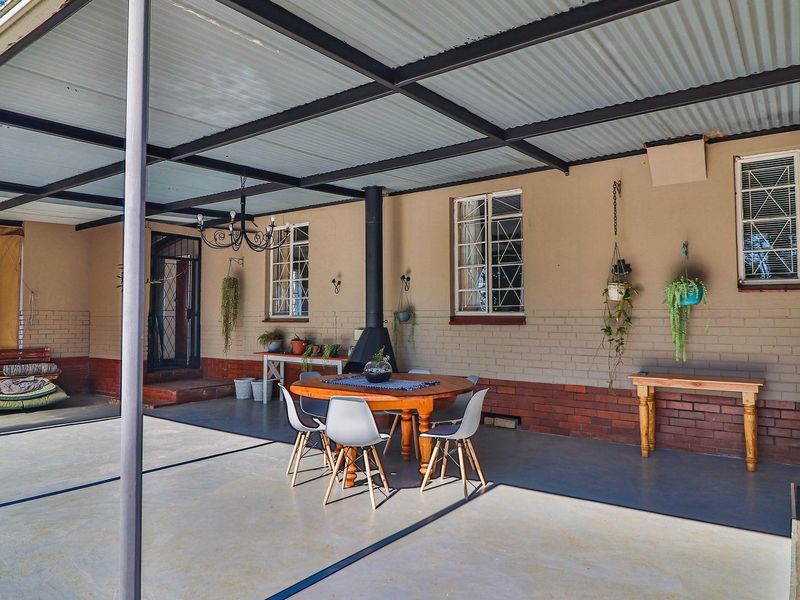 Spacious covered patio featuring a corrugated metal roof, steel support columns, and a built-in fireplace, ideal for outdoor entertaining.