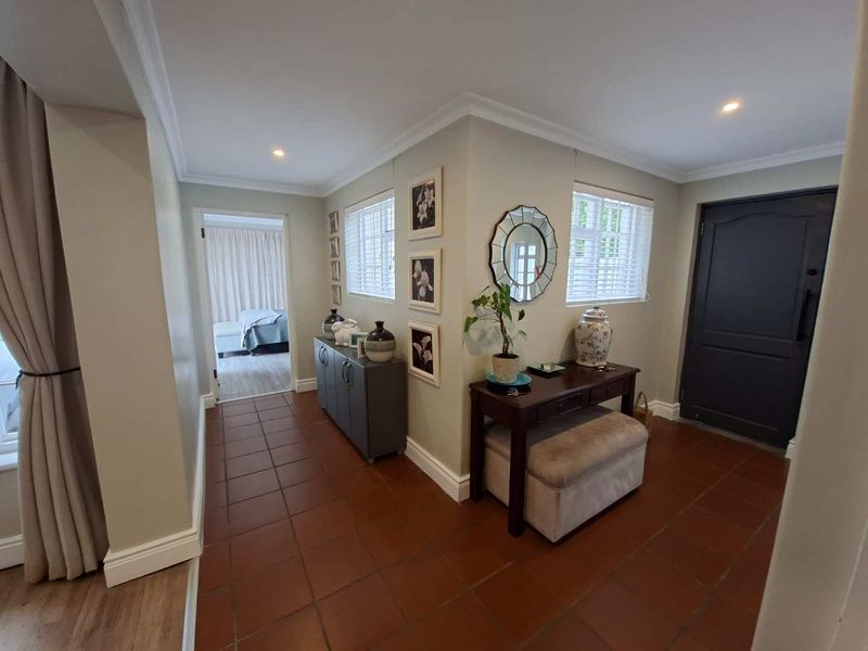 A welcoming entrance hall featuring terracotta floor tiles, recessed downlighting, and neutral wall finishes, providing a clean and well-maintained transition into the home.