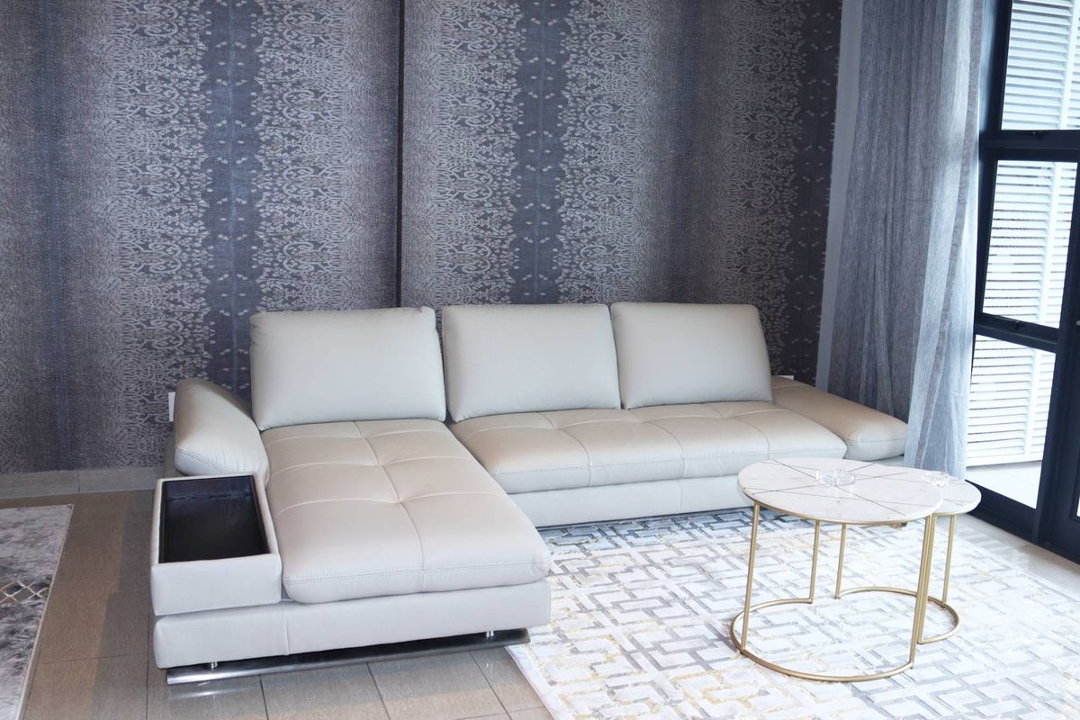 A modern living room featuring a textured feature wall, tiled flooring, and large glass sliding doors providing natural light and access to the exterior.
