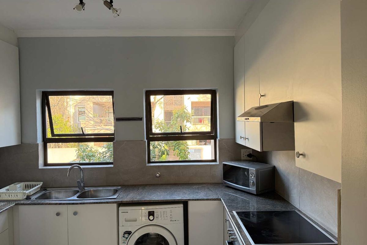 Functional kitchen featuring granite countertops, built-in cabinetry, a double sink, and integrated electric hob with extractor fan, offering a practical workspace.