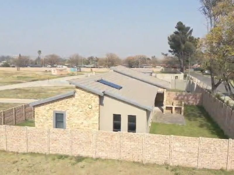 Aerial view of a residential property featuring a brick and plaster exterior, solar water heating system, and a fully enclosed yard with a built-in braai.