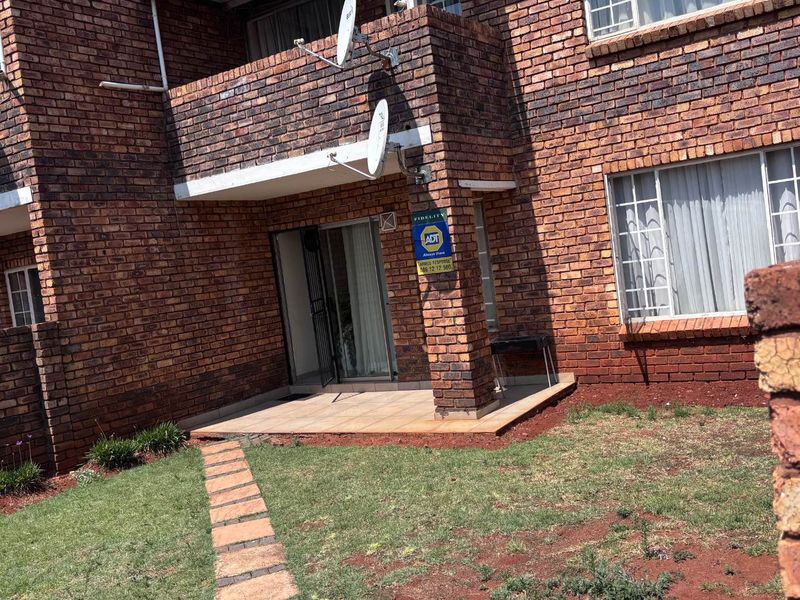 Ground floor apartment exterior featuring a face brick facade, tiled patio area, sliding door access, and a small private garden space.