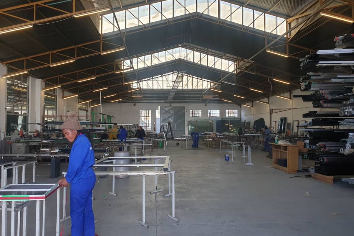 Spacious industrial warehouse featuring high ceilings with exposed steel trusses, translucent roof panels for natural light, and durable concrete flooring.