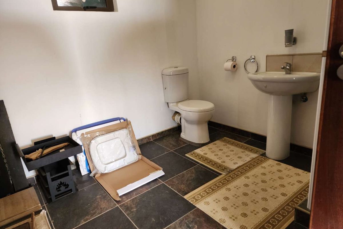 A functional bathroom featuring a pedestal sink, a standard toilet, and dark floor tiling.