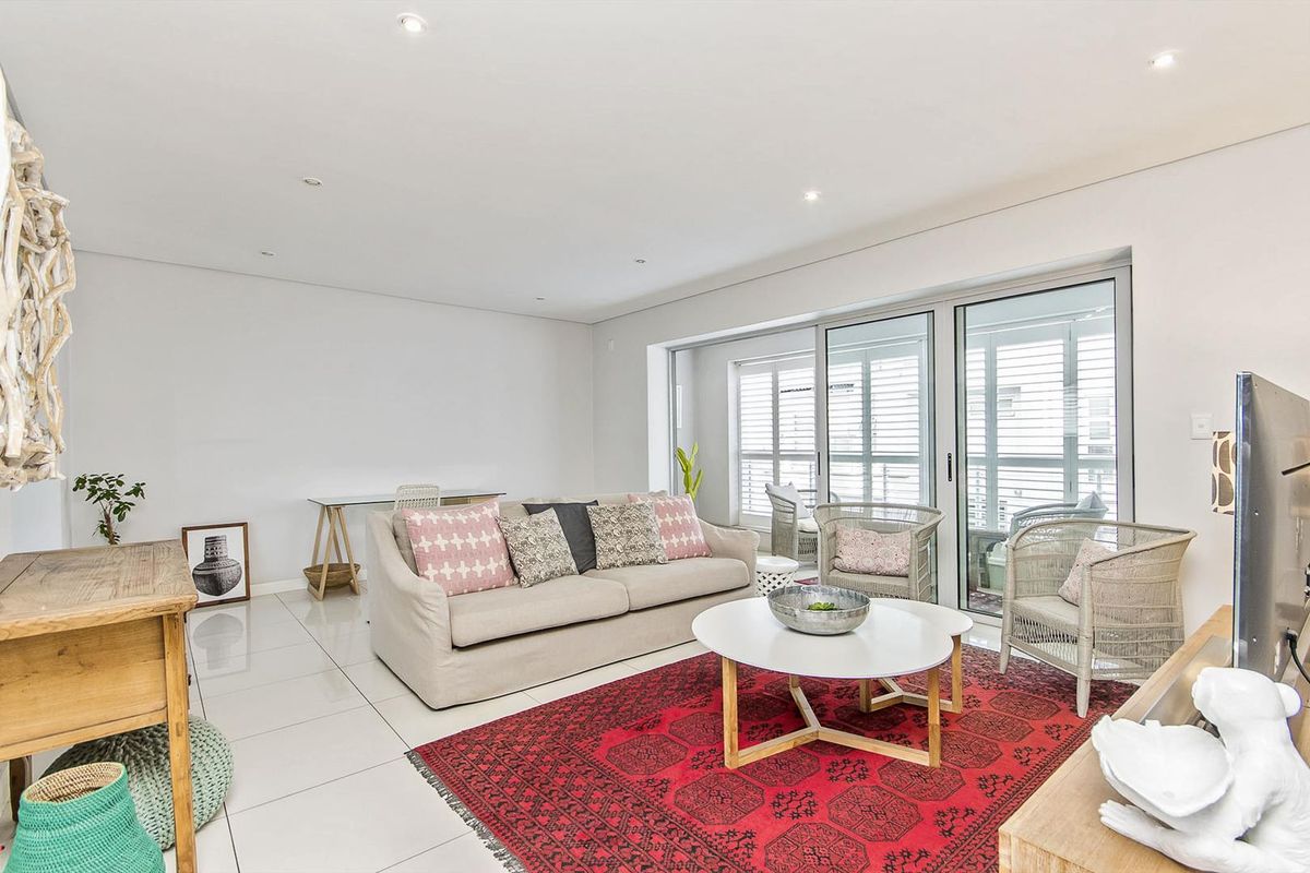 Bright and spacious living area featuring large sliding glass doors that open onto a patio, complemented by modern tiled flooring and recessed downlighting.