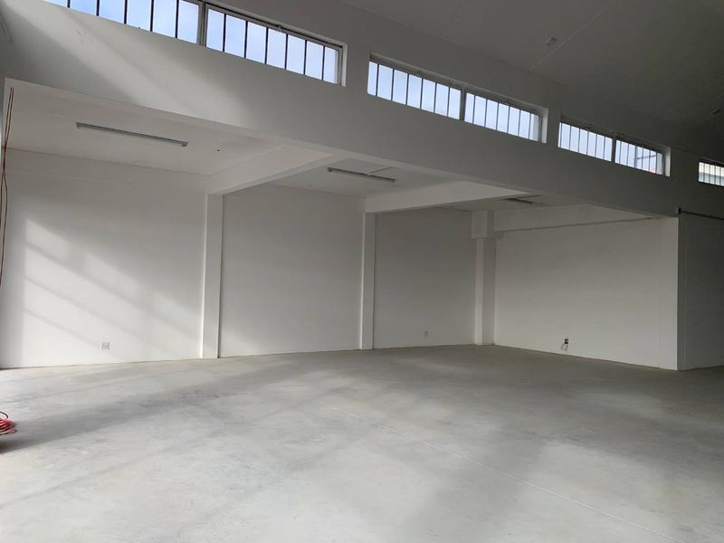 Spacious open-plan retail area featuring high ceilings, clerestory windows for natural light, and polished concrete flooring, suitable for various commercial uses.