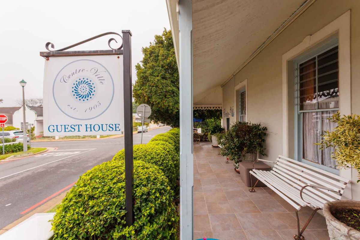 A charming covered veranda at the front of the guest house, featuring tiled flooring and classic sash windows overlooking the street.