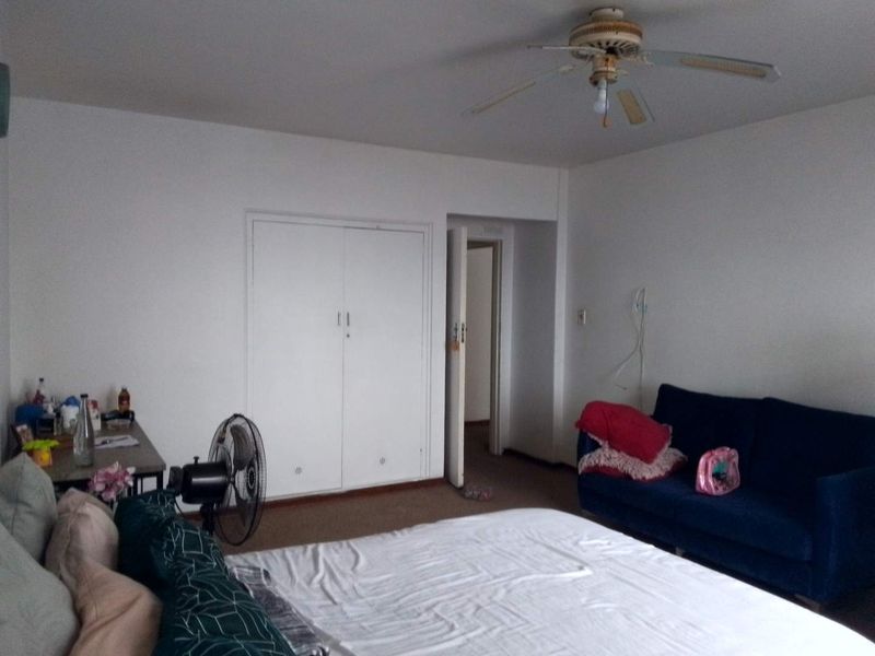 A bedroom featuring carpeted flooring, a ceiling fan, and a built-in wardrobe with white doors.