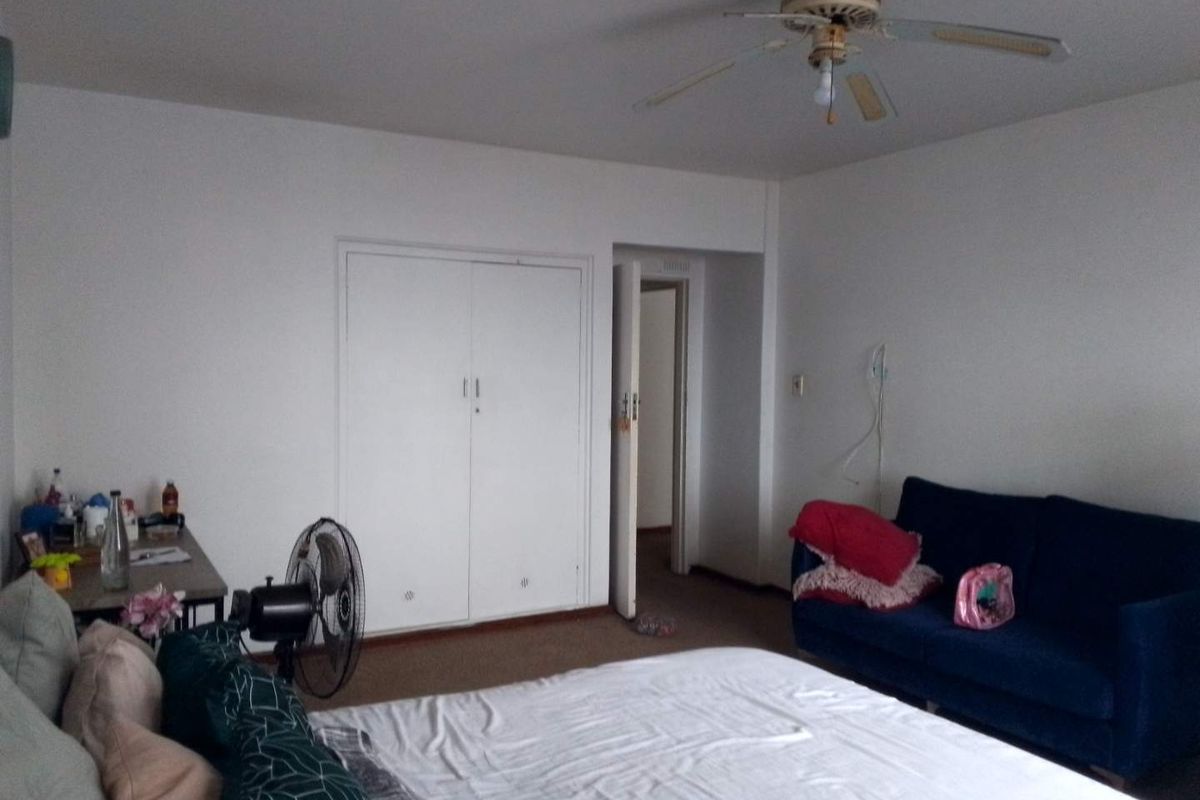 A bedroom featuring carpeted flooring, a ceiling fan, and a built-in wardrobe with white doors.
