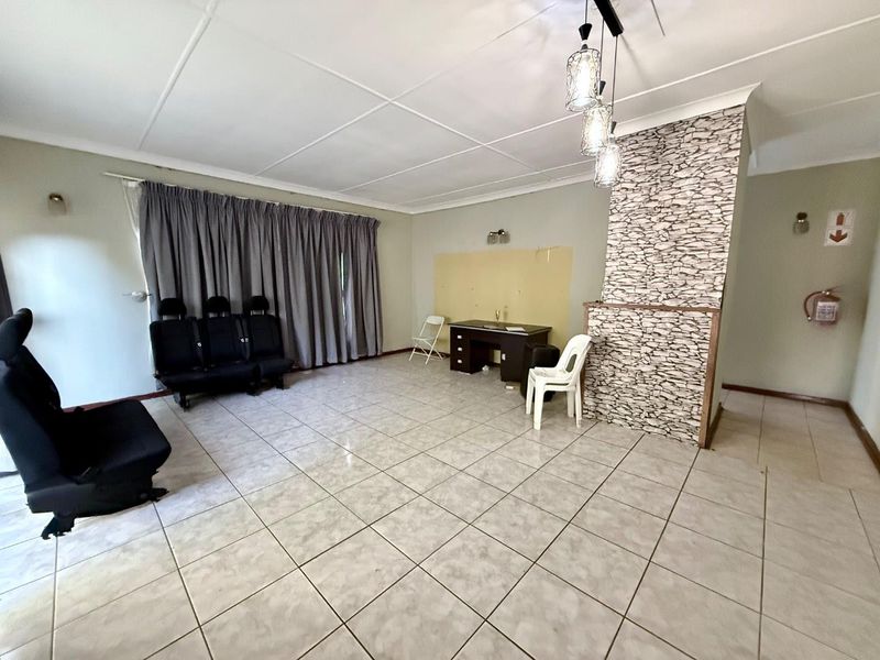 Spacious living area featuring tiled flooring, a stone-cladding feature wall, and pendant lighting, offering a blank canvas for interior design updates.