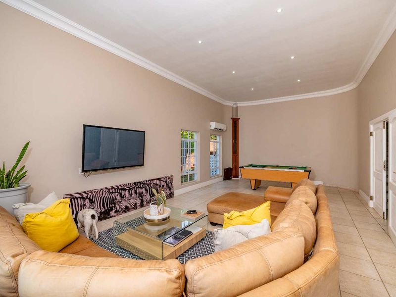 Spacious living area featuring tiled flooring, recessed downlighting, coved ceilings, and a wall-mounted air conditioning unit.