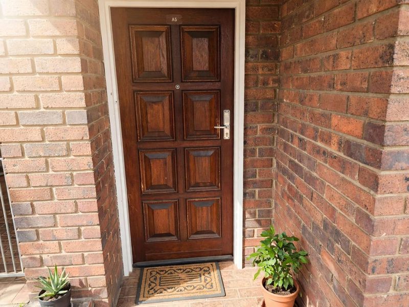 A private apartment entrance featuring a solid timber panelled door set within a classic face-brick exterior wall.