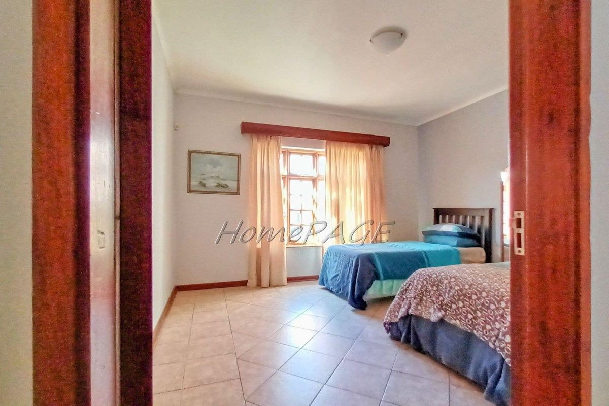 A bedroom featuring tiled flooring and a window with curtain pelmet, viewed from the doorway.