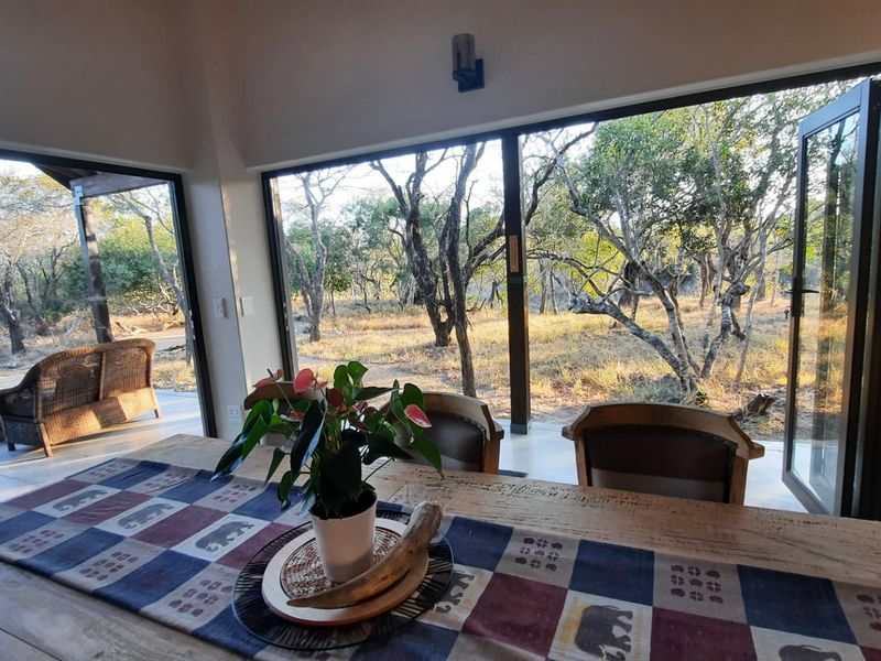 Open plan living area featuring large bi-fold doors that open onto a patio, providing seamless indoor-outdoor flow and views of the surrounding bushveld.