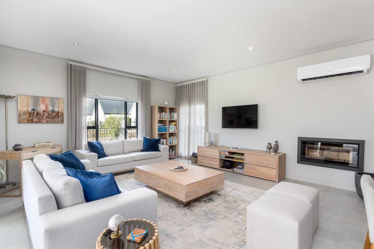 A bright and modern living room featuring tiled floors, a built-in fireplace, and a wall-mounted air conditioning unit.