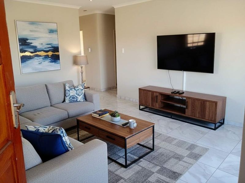 A well-maintained living room featuring neutral tiled flooring and recessed downlighting, providing a clean and comfortable space.