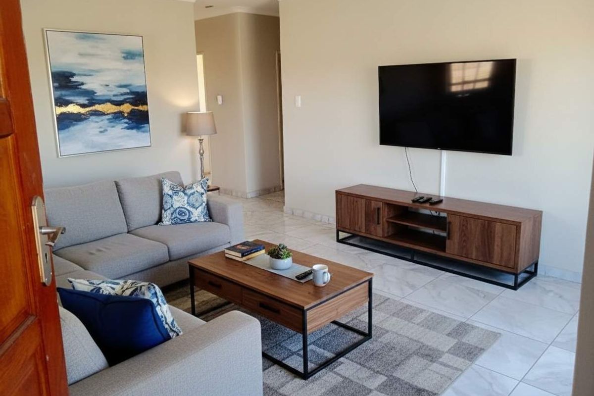 A well-maintained living room featuring neutral tiled flooring and recessed downlighting, providing a clean and comfortable space.