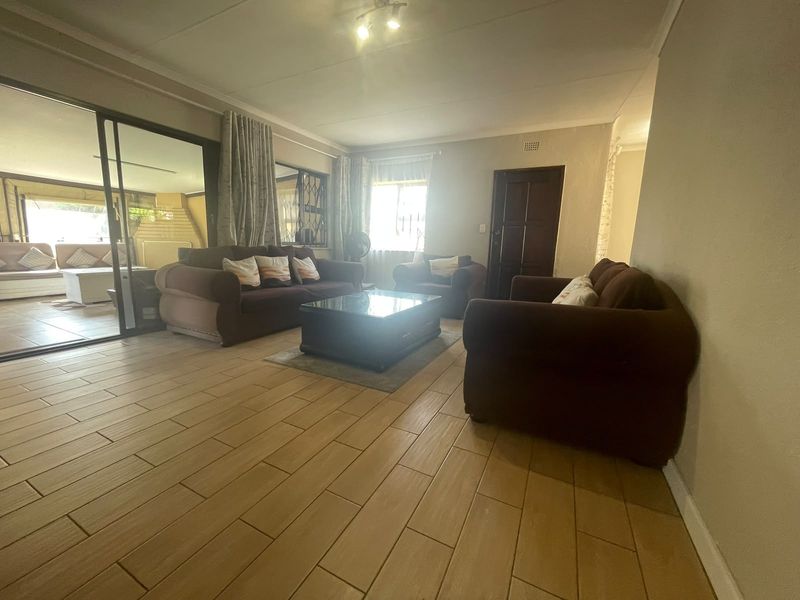 Spacious living room featuring tiled flooring and large sliding glass doors that provide access to an adjoining patio area.