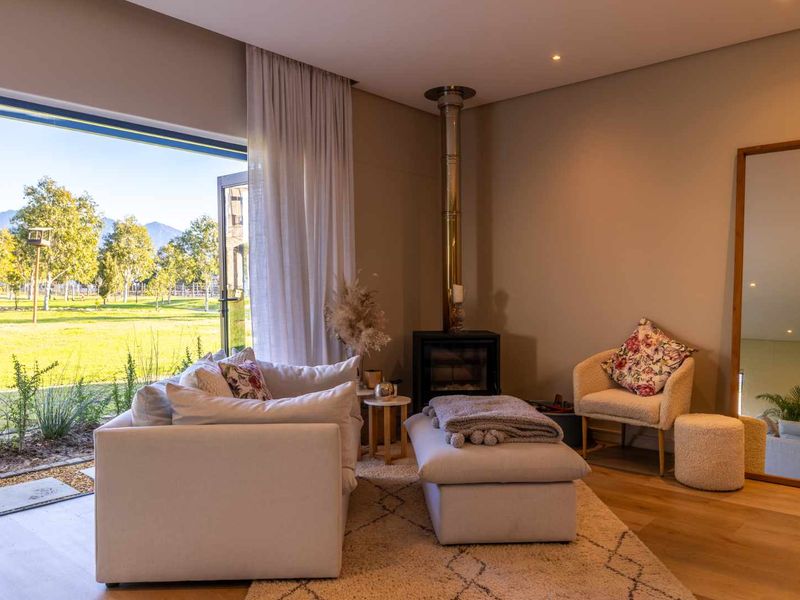 A bright living room featuring a modern freestanding fireplace, hardwood flooring, and large sliding glass doors that open to a scenic garden view.