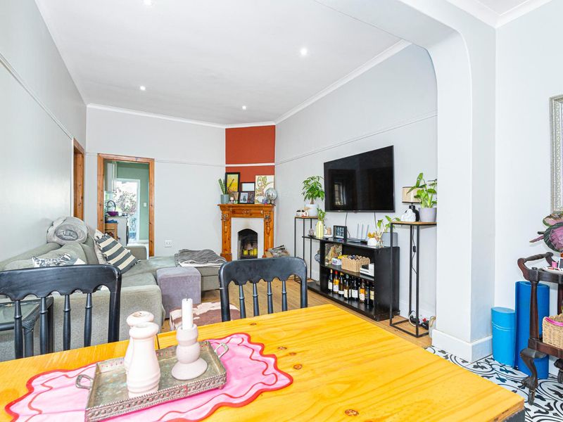 Open plan living area featuring a character fireplace with timber mantelpiece, recessed downlights, and a decorative archway connecting to adjacent spaces.