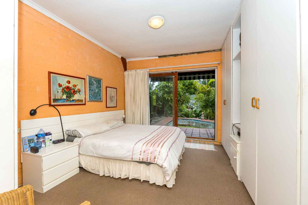 Bedroom featuring built-in wardrobes, carpeted flooring, and sliding glass doors providing direct access to the outdoor patio and pool area.
