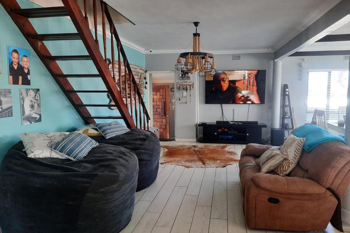 A living room featuring a wooden staircase, tiled flooring, and a central light fixture, providing a functional and open living space.