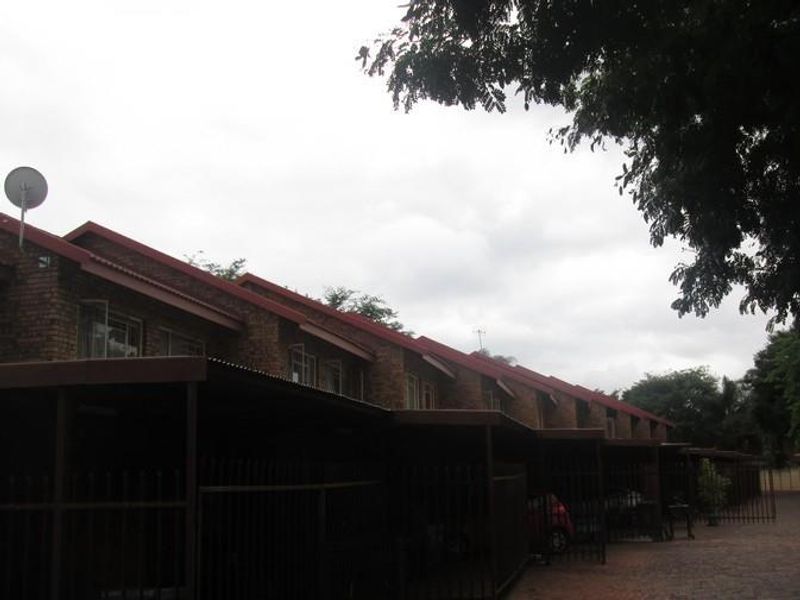 Exterior view of a multi-unit apartment complex featuring brick facades, pitched roofs, and dedicated carport parking structures.