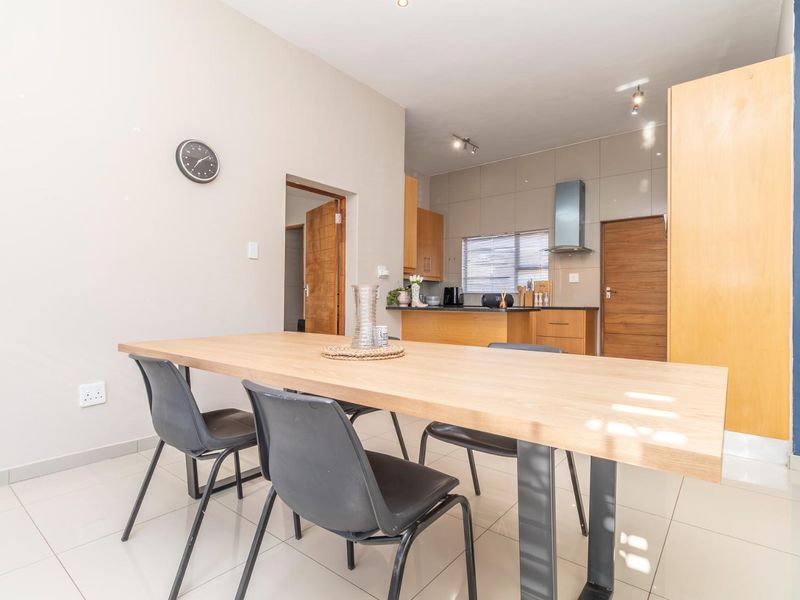 Open-plan dining and kitchen area featuring modern tiled flooring, wooden cabinetry, and integrated kitchen fixtures with a clean, functional layout.