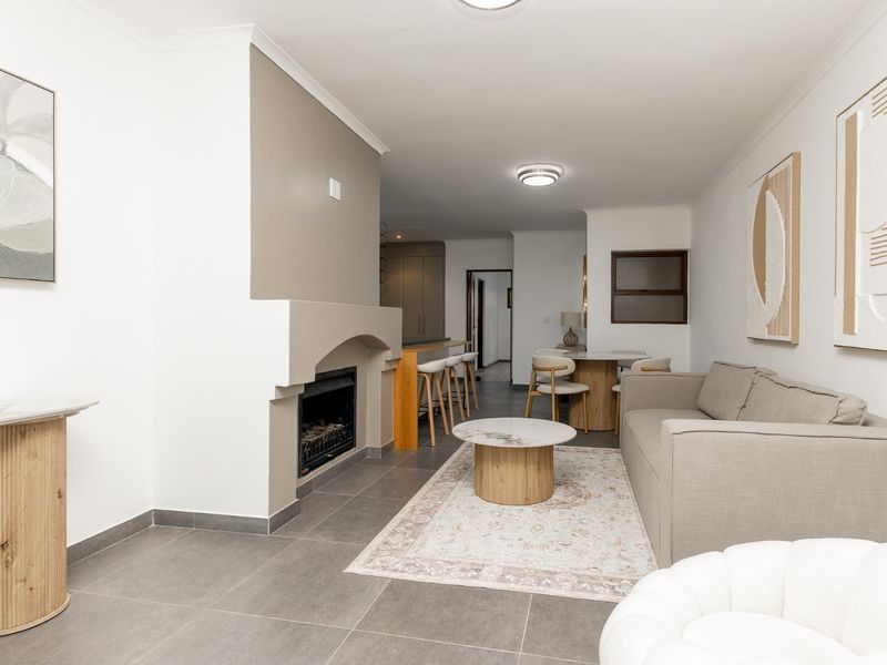 Spacious open-plan living area featuring a built-in fireplace, modern tiled flooring, and a breakfast bar connecting to the kitchen space.