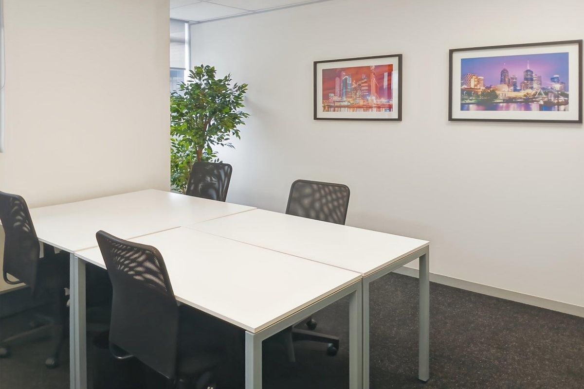 A clean, professional office space featuring neutral walls, carpeted flooring, and a suspended ceiling, suitable for a productive work environment.