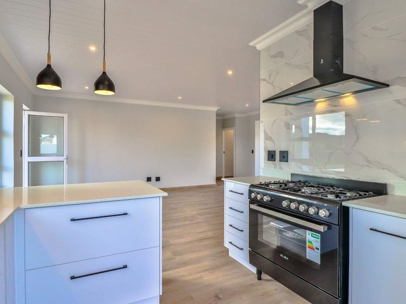 Modern open-plan kitchen featuring a gas stove, extractor fan, marble-look splashback, and quartz countertops, flowing into a bright, neutral living area.