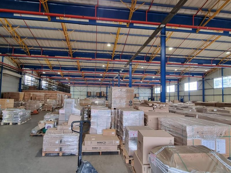Spacious industrial warehouse featuring high-clearance steel truss roofing, concrete flooring, and large roller shutter doors for efficient logistics and storage operations.