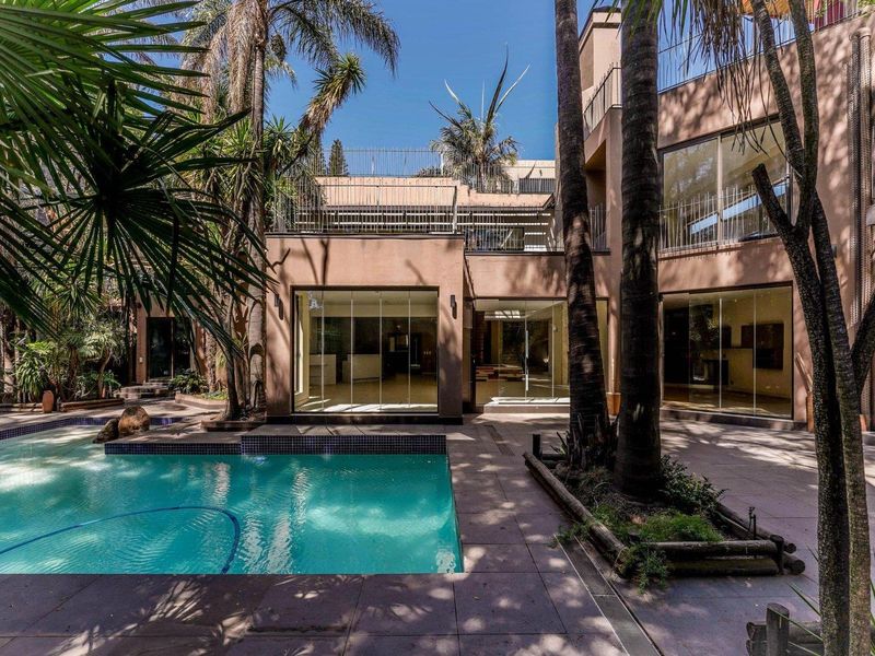 A well-maintained rear exterior featuring a swimming pool, paved patio area, and large glass doors leading into the multi-level residence.