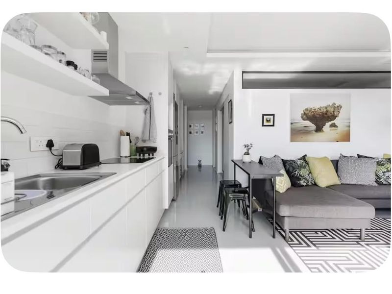Modern open-plan apartment featuring a sleek white kitchen with integrated appliances and a seamless transition into the living area.
