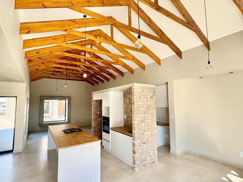 Spacious open-plan kitchen and living area featuring high vaulted ceilings with exposed timber trusses, a central island, and modern finishes.