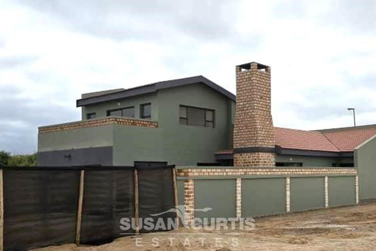Exterior view of a modern two-story property featuring a prominent brick chimney, tiled roof, and a perimeter boundary wall.