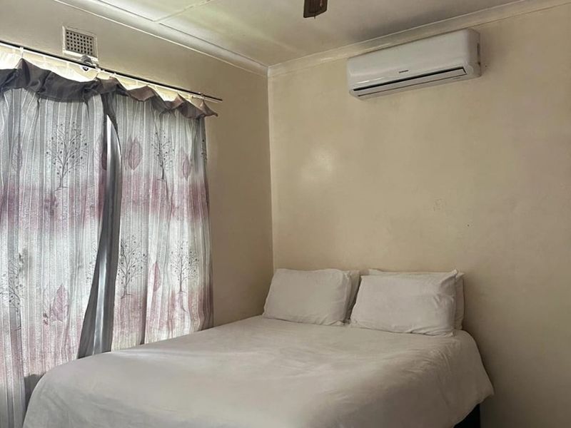 A bedroom featuring tiled flooring, a ceiling fan, and a wall-mounted split-system air conditioner.