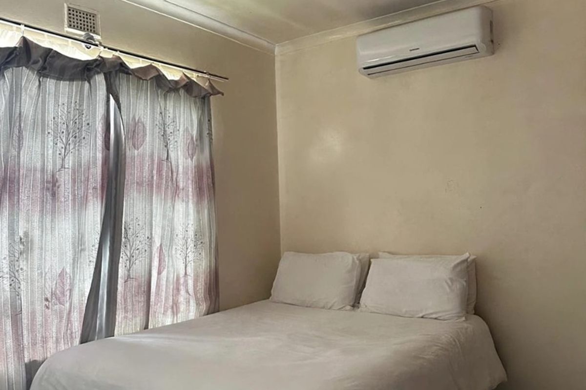 A bedroom featuring tiled flooring, a ceiling fan, and a wall-mounted split-system air conditioner.