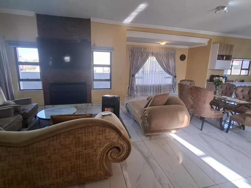 Spacious open-plan living and dining area featuring tiled flooring, a brick-surround fireplace, and an integrated kitchen space.