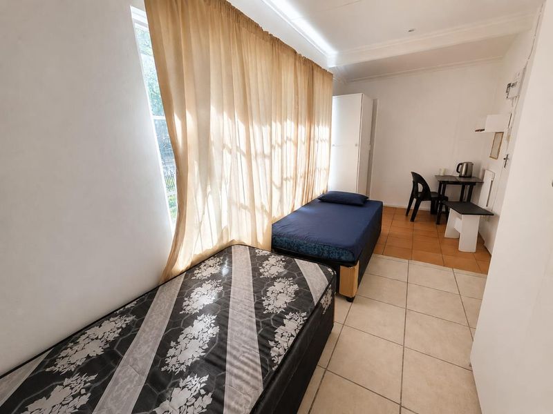 A functional bedroom featuring tiled flooring and a built-in wardrobe, offering a simple and practical living space.