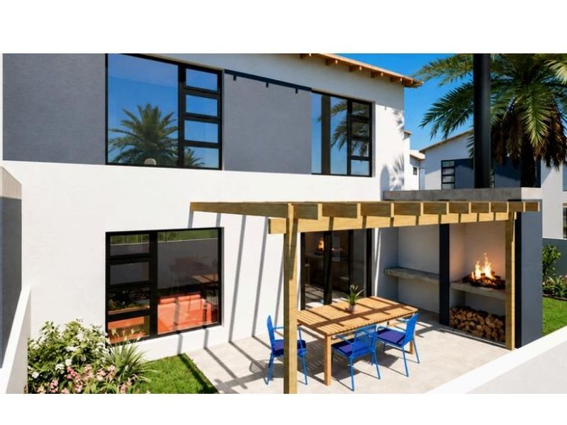 A modern rear patio featuring a wooden pergola, built-in braai, and direct access to the interior through sliding doors.