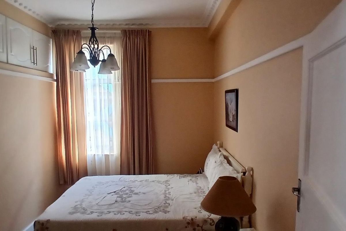 A cozy bedroom featuring built-in overhead cupboards, decorative ceiling cornicing, and a classic picture rail, providing a functional and traditional living space.