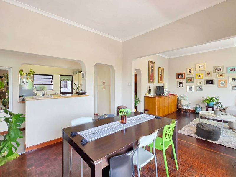 Open plan living and dining area featuring classic parquet flooring, arched transitions, and a functional kitchen with built-in cabinetry and sink.