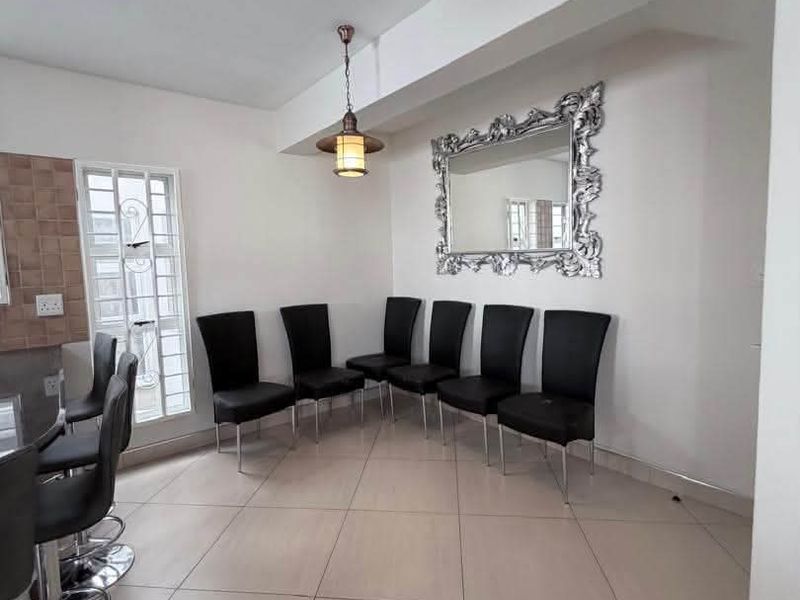 A dining area featuring neutral tiled flooring, a pendant light fixture, and a window with security bars.