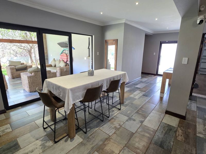 Open-plan living area featuring modern wood-look tiled flooring, recessed downlights, and large sliding glass doors providing seamless access to the outdoor patio.